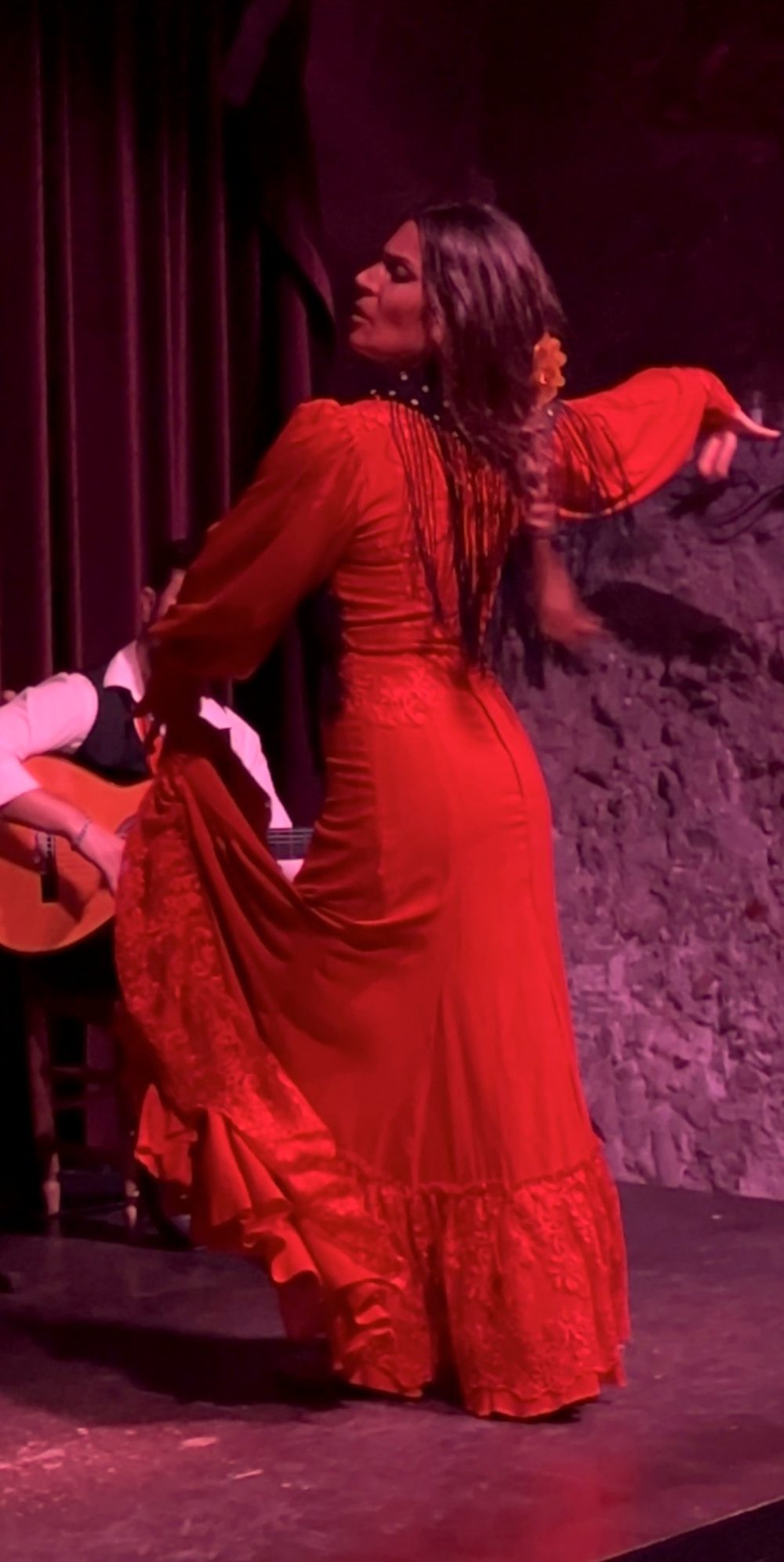 Flamenco dancer in a red dress performing against the stone wall at Palau Dalmases